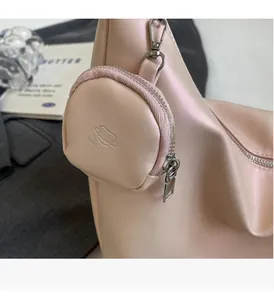 Detailed close-up of a light pink shoulder bag with a matching round mini charm pouch