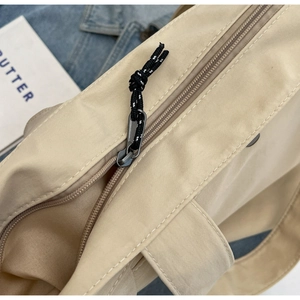 Detail of smooth zipper closure with woven pull cord on a beige nylon tote bag
