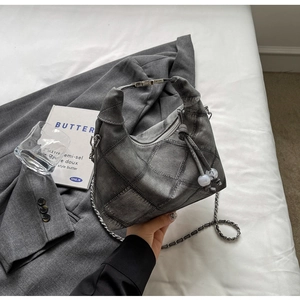 Detail of grey denim dumpling bag featuring patch craftsmanship and pearl zipper charm