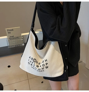 Detail view of large canvas tote bag with black letter print and adjustable shoulder strap