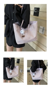 Gros plan sur un sac cabas tressé lilas avec porte-clé en peluche et anses en cuir