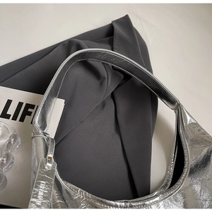 Detailed macro view of the silver hobo bag featuring metallic pleated texture and logo tag