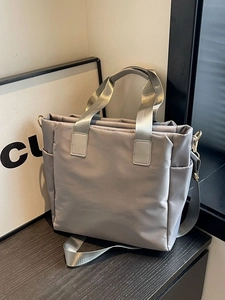 Puffy quilted tote bag in light grey with webbed handles and adjustable strap