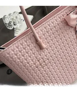 Detail view of a pink woven tote bag with fine textures and floral silk scarf accessory