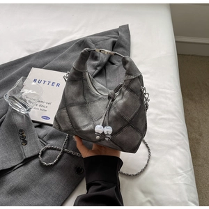 Detailed patchwork denim hobo bag featuring grey quilted textures and stylish chain strap
