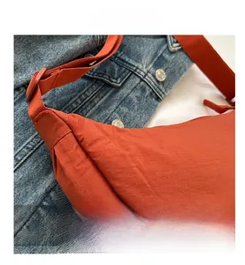 Detailed macro view of orange dumpling bag with pleated texture on blue denim background