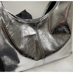 Detail of silver metallic tote bag featuring premium wrinkled texture and reinforced stitching