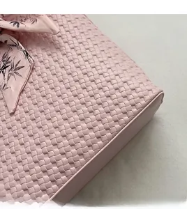 Detail of pink woven leather tote with floral silk scarf accessory and soft texture