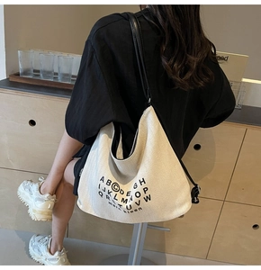 Detailed back view of a minimalist cream canvas tote bag with black shoulder strap