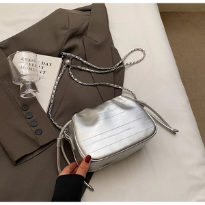 Détail d'un mini sac seau argenté texturé avec bandoulière chaîne et fermeture cordon