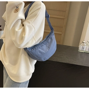 Detail of blue nylon crescent bag showing smooth texture and adjustable shoulder strap