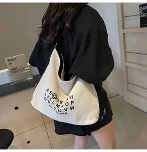 Side view of large canvas tote bag with black letter print on a female model