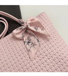 Detail of pink woven tote bag featuring a decorative silk scarf with bamboo patterns