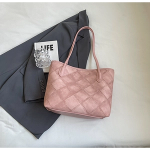 Pink quilted suede tote bag with diamond pattern on white fabric with grey blazer