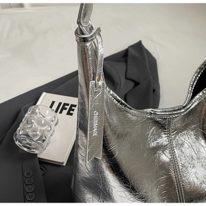 Detailed close-up of metallic silver hobo bag with textured wrinkles and brand tag