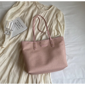 Détail de la texture tissée rose et des anses en cuir sur le grand sac de plage