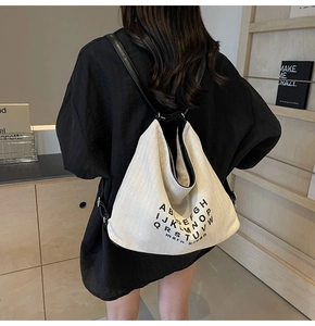 Minimalist beige canvas shoulder bag with black leather straps and letter print detail
