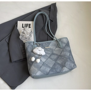 Detail view of a large tote bag with quilted texture and a cute cloud charm accessory