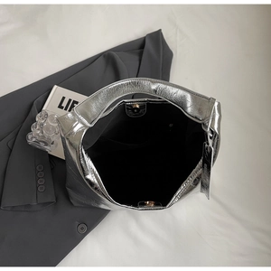 Detail view of silver pleated shoulder bag with magnetic snap closure and black interior lining