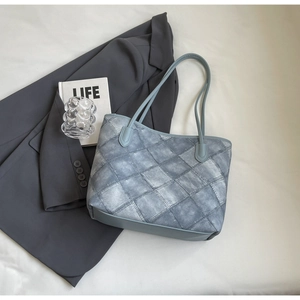 Flat lay showing blue quilted tote bag with thin straps and Life book on white cloth