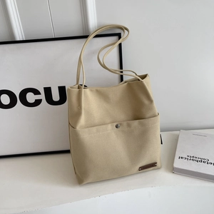 Canvas bucket shoulder bag with front pocket and leather tag in beige minimalist style