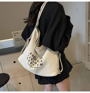 Close-up of cream canvas hobo bag with herringbone texture on a model shoulder