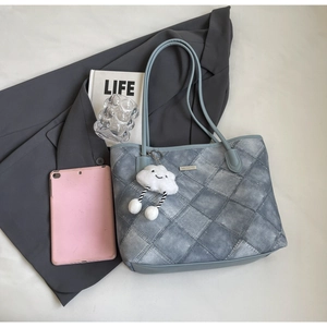 Detail shot of blue quilted tote bag with metal nameplate and plush cloud charm
