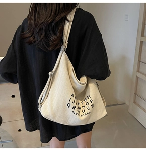 Close-up of off-white canvas tote bag featuring stylish black letter prints and wide strap