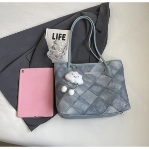Flat lay of blue quilted tote bag with white cloud plush charm and urban accessories