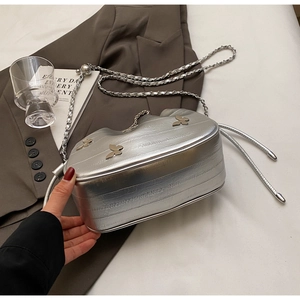 Détail du sac seau argenté à chaîne avec trois breloques papillon dorées et fini métallisé