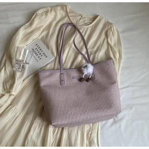 Détail du sac cabas tissé violet clair avec charm pompon et rivets dorés élégants