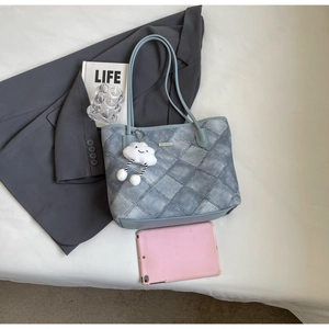 Detail of blue denim tote bag with quilted texture and cloud plush charm accessory