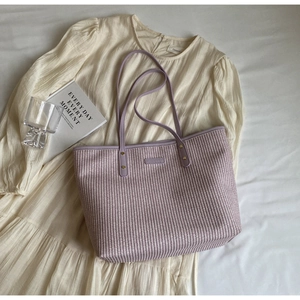 Gros plan sur la texture tissée lilas du cabas avec anses en cuir et logo argenté