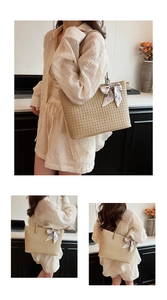 Macro detail of beige woven straw tote bag featuring a decorative silk scarf bow