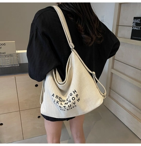 Close-up of the large cream canvas hobo bag with black letter print and wide shoulder strap