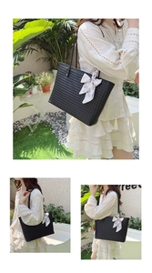 Detail of black woven tote bag with silk scarf accessory in a sunny outdoor setting