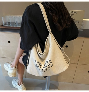Close-up of cream canvas tote bag featuring minimalist black typography and texture