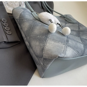 Detail of blue denim patchwork tote bag with plush charm and smooth contrast base
