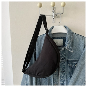 Detail of minimalist black crescent dumpling bag with adjustable wide fabric strap