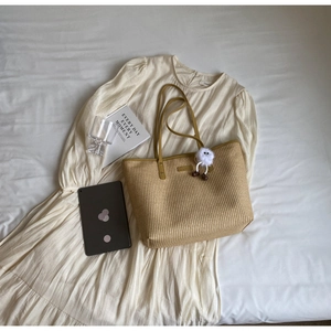 Détail du sac cabas en paille avec bandoulière en cuir jaune et pendentif en peluche