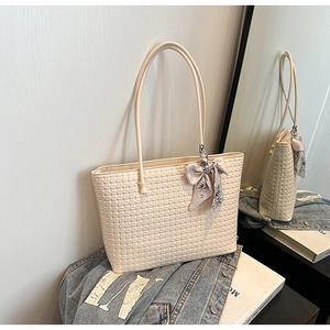Detail of off-white woven leather tote bag with floral scarf handle and blue denim jacket