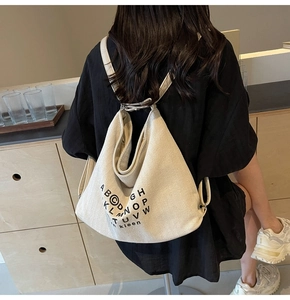 Detail of a large off-white canvas tote bag showing twill texture and shoulder straps