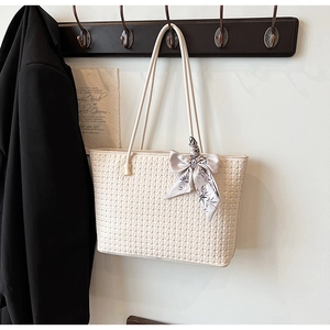 Detail of cream woven tote bag texture featuring decorative floral silk scarf on handle