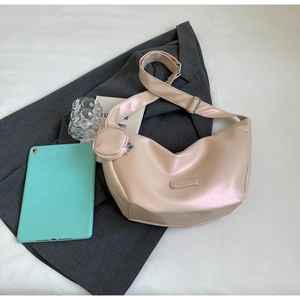 Detail of minimalist apricot dumpling crossbody bag with a round mini pouch on grey blazer