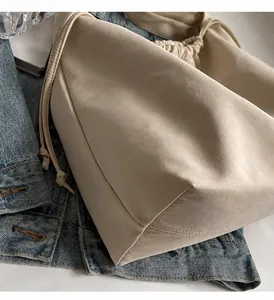 Nahaufnahme der beigen Kordelzug-Beuteltasche mit feiner Textur auf Denim-Stoff