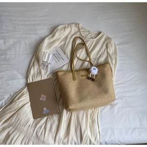 Détail du sac fourre-tout en paille avec lanières en cuir et pendentif mascotte