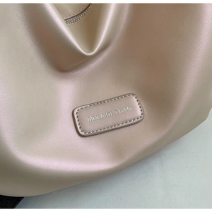 Detailed close-up of pearlescent leather texture and brand tag on silver shoulder bag