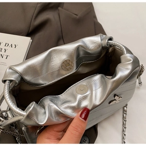 Vue détaillée du sac bourse argenté avec fermoir magnétique et détail de papillon en métal