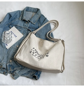 Detail of canvas tote bag with letter print and light khaki leather reinforced bottom