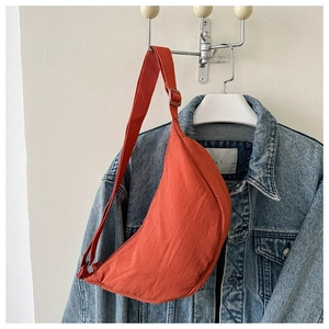 Brick red dumpling crossbody bag with adjustable strap displayed on a white hanger
